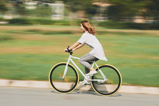 Happy excited young woman riding bicycle at high speed - Photo, Image