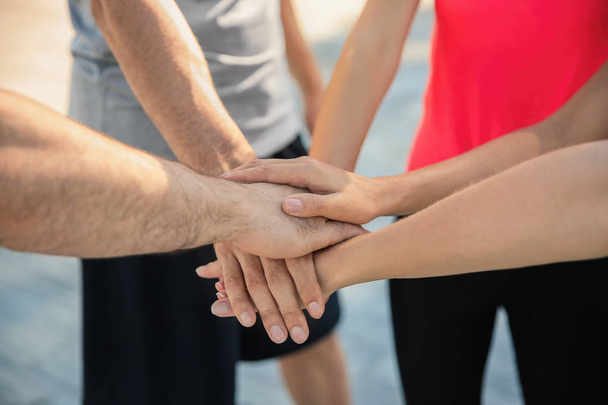 Group of sporty people putting hands together outdoors, closeup - Photo, Image