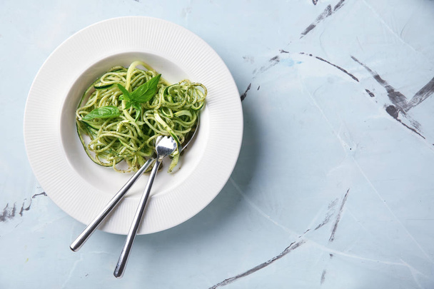 Plate of spaghetti with zucchini and pesto sauce on table - 写真・画像