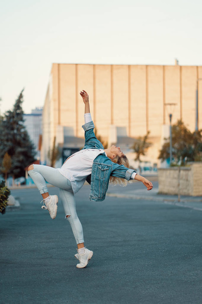 Young beautiful girl dancing, urban culture concept. Beautiful woman dancing in the city on buildings background. Beautiful body dancing position. - 写真・画像