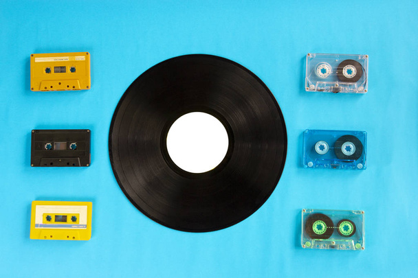 Вид сверху на старые виниловые пластинки и кассеты на синем фоне
 - Фото, изображение