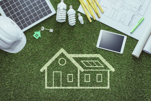 Proyectos de viviendas sostenibles y concepto de construcción verde: anteproyecto, panel solar y herramientas sobre césped exuberante
 - Foto, Imagen
