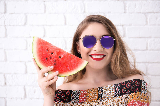 Beautiful young woman with slice of tasty watermelon near brick wall - Фото, зображення