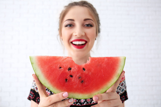 Beautiful young woman with slice of tasty watermelon on light background - Photo, Image
