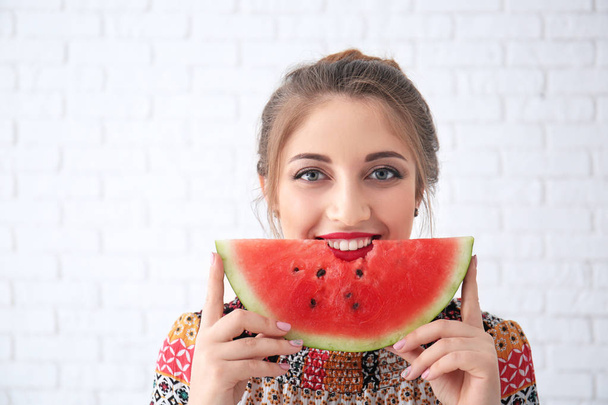 schöne junge Frau mit Scheibe leckerer Wassermelone auf hellem Hintergrund - Foto, Bild
