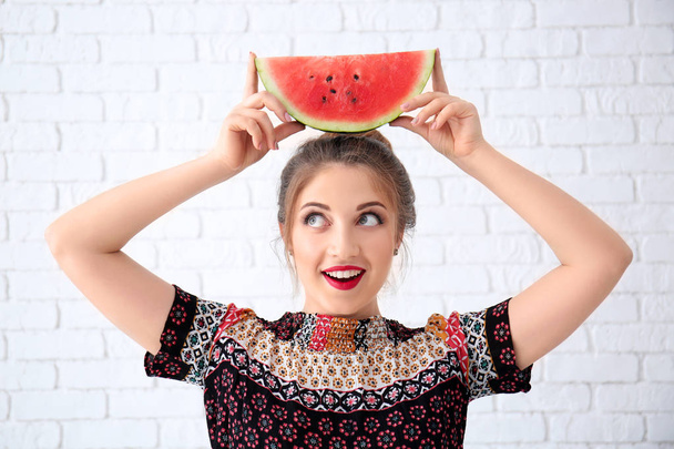 Krásná mladá žena s plátkem chutné meloun poblíž cihlová zeď - Fotografie, Obrázek