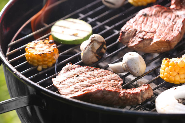 Smakelijke steaks en groenten koken op de barbecue grill, close-up - Foto, afbeelding