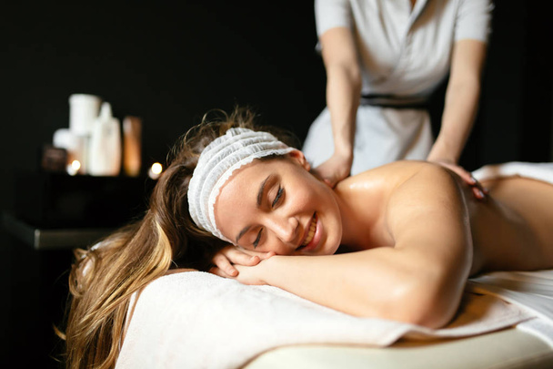 Beautiful woman enjoying massage treatment given by therapist - Foto, afbeelding
