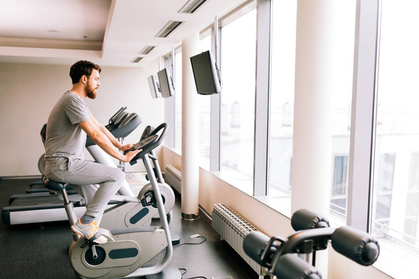 Man cardio training on a bicycle in a gym - Fotoğraf, Görsel