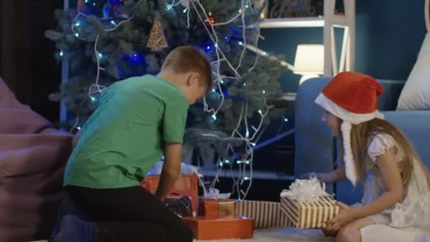 Happy kids unwrapping Christmas gifts at home - Video
