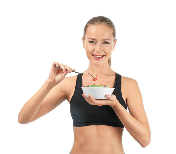 Mujer deportiva comiendo ensalada de verduras frescas sobre fondo blanco
 - Foto, imagen