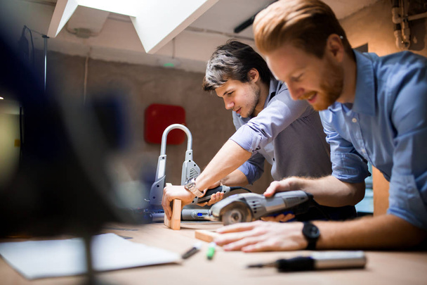 Two creative designers working in workshop with precision tools manufacturing a new product - Fotoğraf, Görsel