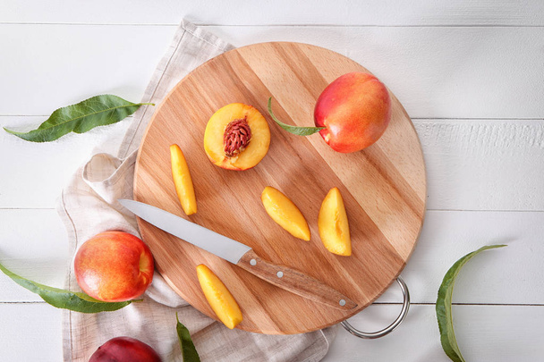 frische süße Pfirsiche mit Holzbrett auf weißem Tisch - Foto, Bild