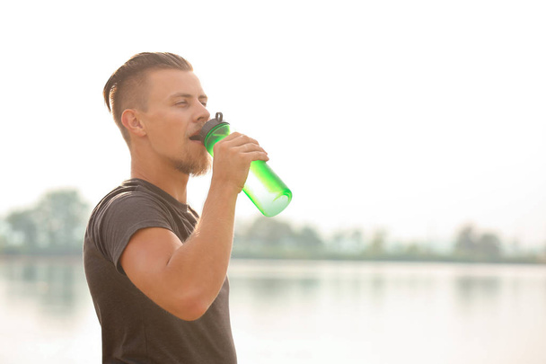 İçme suyu sportif genç adam açık havada eğitimden sonra - Fotoğraf, Görsel