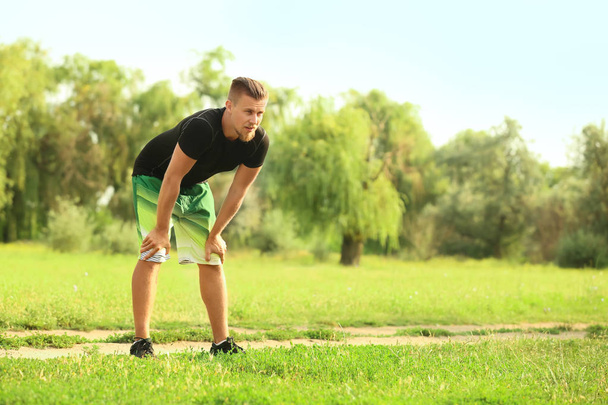 Sportlicher junger Mann ruht sich nach Training im Freien aus - Foto, Bild