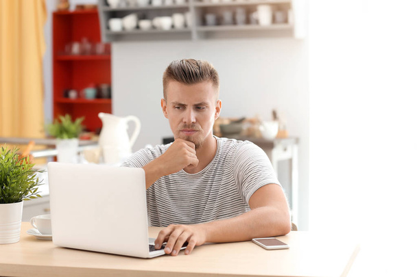 Emotionele freelancer werkt op laptop in de keuken - Foto, afbeelding