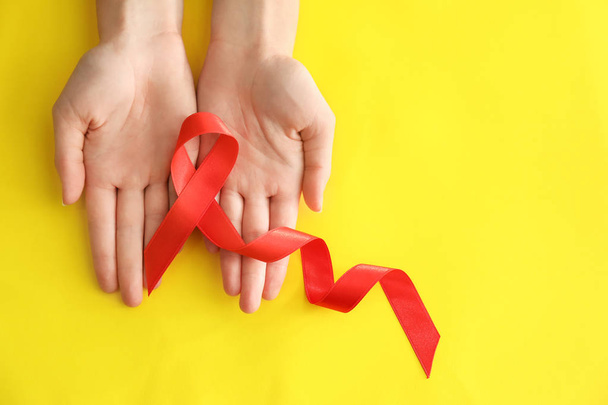 Woman holding red ribbon on color background. AID awareness concept - Photo, Image