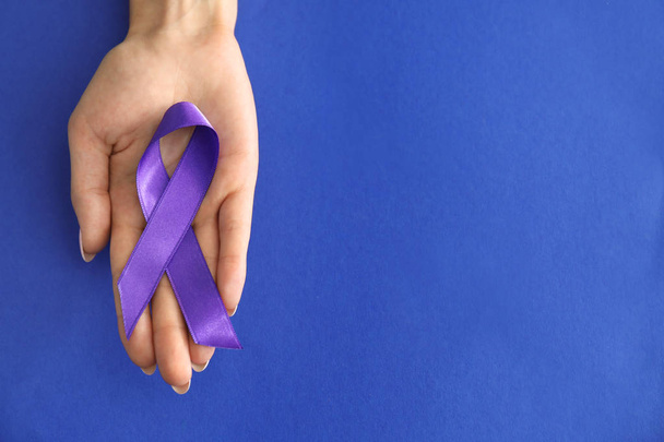 Mujer sosteniendo cinta púrpura sobre fondo de color. Concepto de conciencia sobre el cáncer de páncreas
 - Foto, Imagen