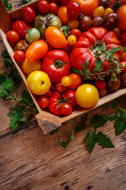 Ripe tomatoes in a crate on rustic wooden background - Fotó, kép