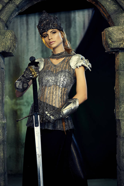 girl in armor with a sword and a crown - Фото, изображение