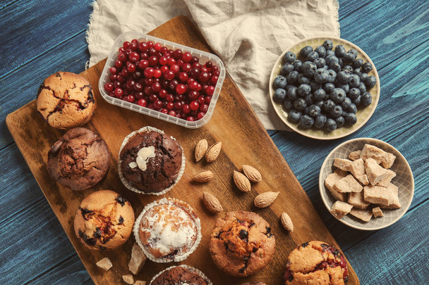 Planche avec de savoureux muffins et baies sur table en bois
 - Photo, image