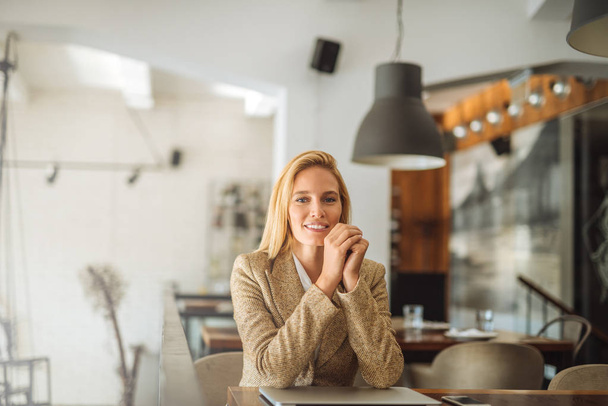 Photo of a smiling young business woman sitting at the table in the cafe. - Photo, image