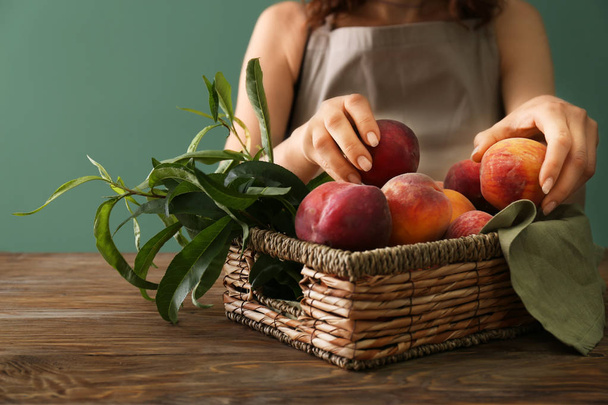 Woman with fresh peaches at wooden table - Фото, зображення