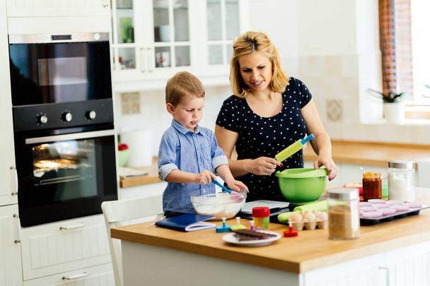 Child helping mother prepare muffins in kitchen - Φωτογραφία, εικόνα