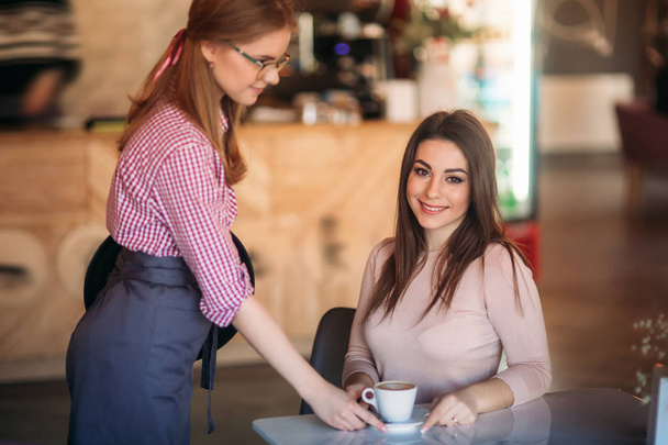 Официантка предлагает чашку кофе в кафе. капучино
 - Фото, изображение