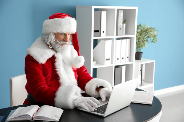 Santa Claus working on laptop at table - 写真・画像