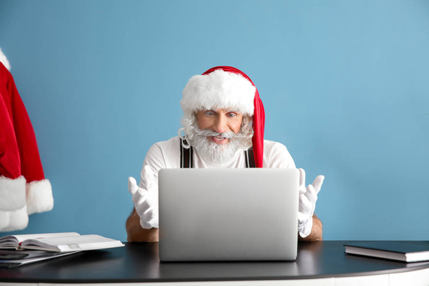 Weihnachtsmann arbeitet am Laptop am Tisch - Foto, Bild