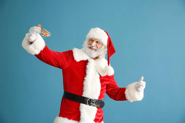 Portrait of Santa Claus playing with toy airplane on color background - Photo, Image