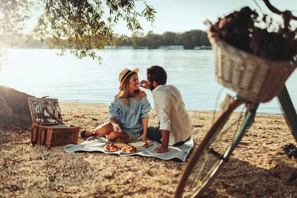 Couple in love enjoying picnic time and food outdoors. - Фото, зображення