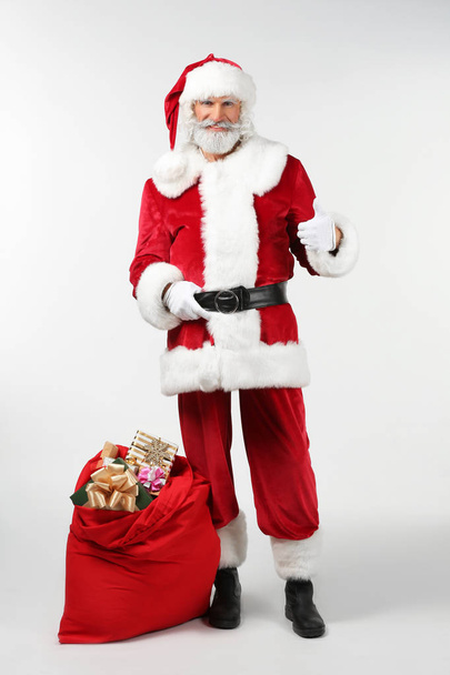 Портрет Санта-Клауса с сумкой, полной подарков на белом фоне
 - Фото, изображение