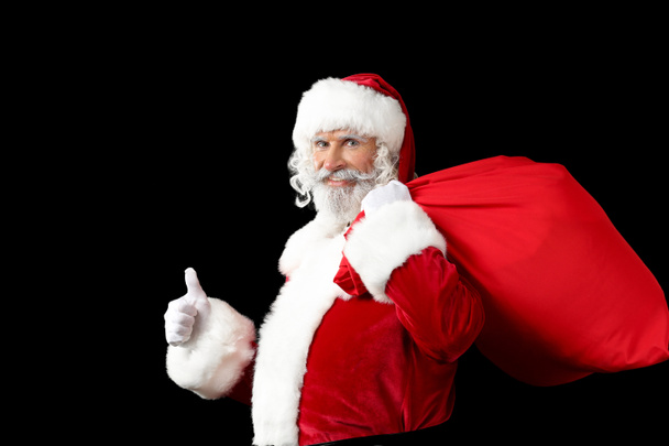 Портрет Санта-Клауса с сумкой, полной подарков на темном фоне
 - Фото, изображение