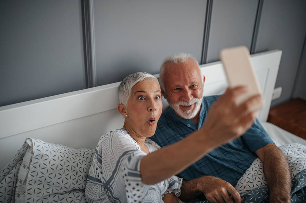 A senior couple is making funny faces while taking a photo for their loved ones. - Foto, Imagen
