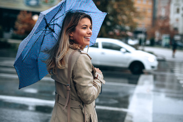 Beautiful woman with umbrella on a rainy day. - Фото, изображение