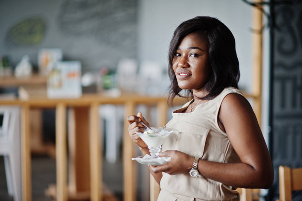 Афро-американських дівчина позувала в кафе і їдять морозиво. - Фото, зображення