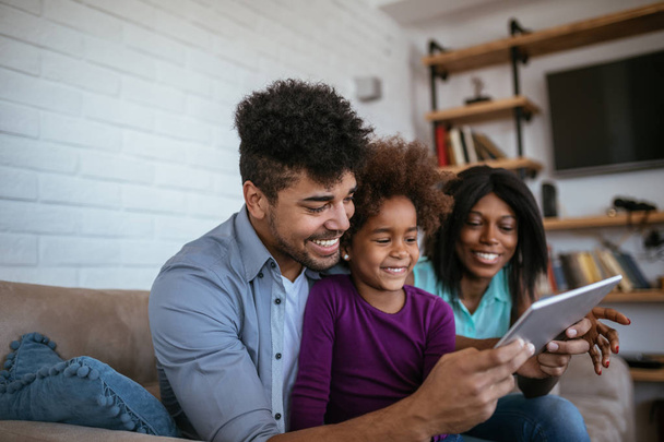 Happy black parents are teaching their daughter by using a tablet. - Φωτογραφία, εικόνα