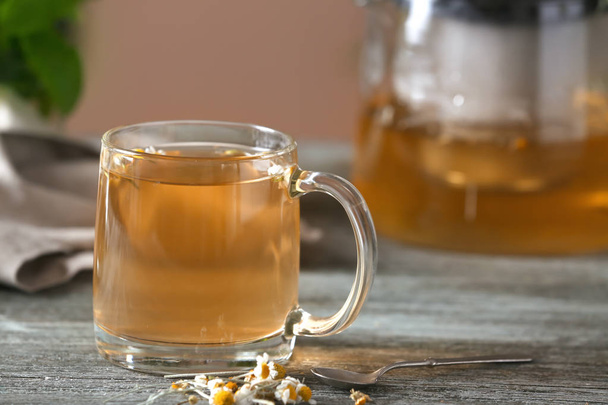 Copa de vidrio de delicioso té de manzanilla en la mesa de madera
 - Foto, imagen