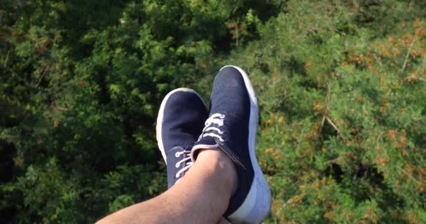 Aerial POV View. Flying over the beautiful forest trees. Aerial camera shot and human legs with blue sneakers in frame. Landscape panorama - Footage, Video