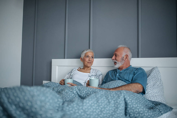 Senior couple drinking morning coffee in bed. - Zdjęcie, obraz