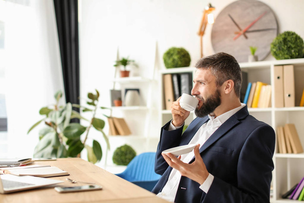 Бизнесмен пьет кофе на рабочем месте
 - Фото, изображение