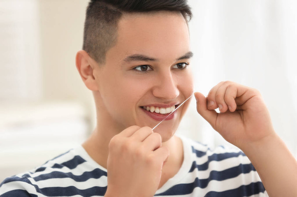 Młody człowiek nitkowanie zębów w domu - Zdjęcie, obraz