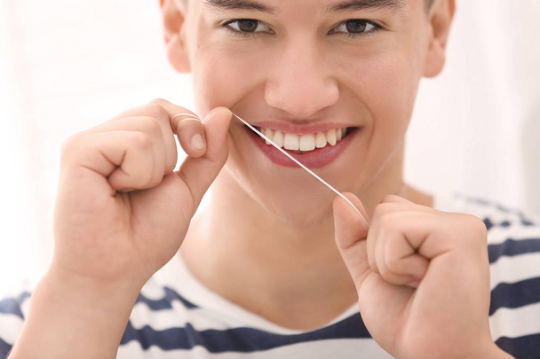Joven hombre usando hilo dental, primer plano
 - Foto, Imagen