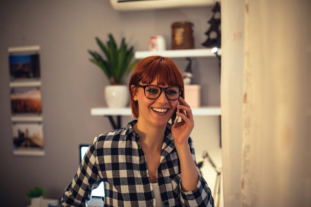 Young business woman talking on the mobile phone at home. - Foto, imagen