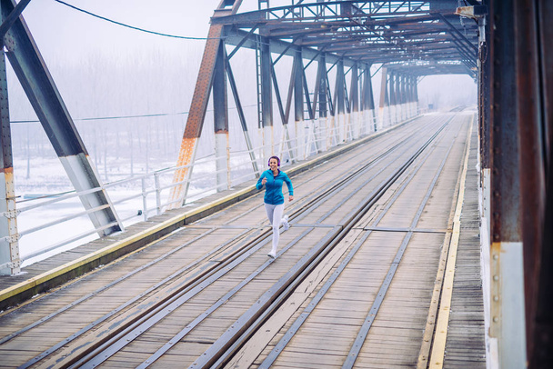 Athlete woman running on the bridge. - Valokuva, kuva