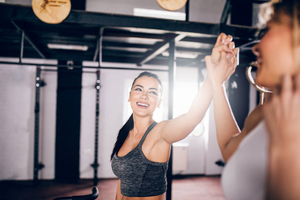 Two athlete woman giving high five in the gym. - Zdjęcie, obraz