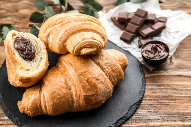 Tasty croissants with chocolate paste on slate plate - Photo, Image