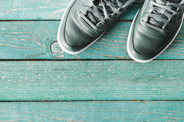 Green leather sneakers on green wooden background  - Foto, immagini
